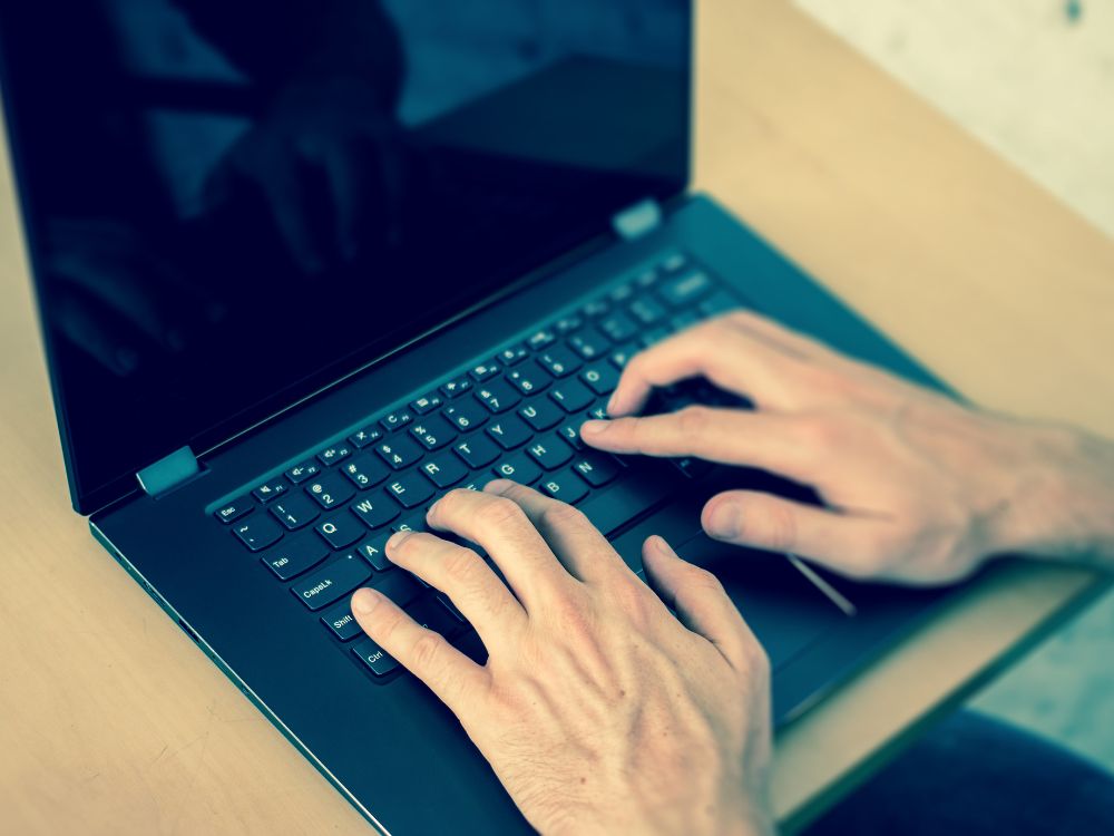 Mãos digitando em notebook, simbolizando administração de site e cuidados com a segurança no WordPress.