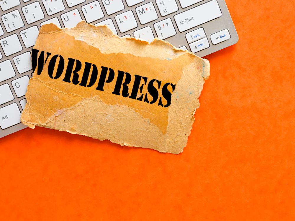Papel com a palavra WordPress sobre teclado branco, destacando o tema de segurança em sites com a plataforma.