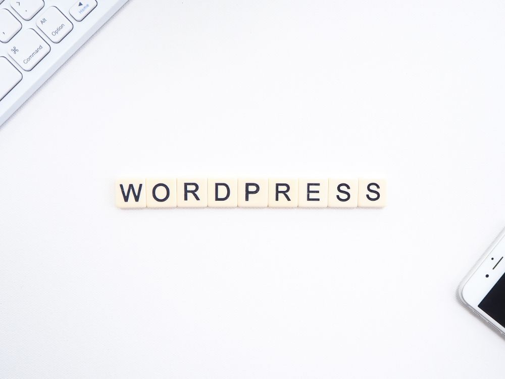 Palavra WordPress formada por blocos sobre mesa branca, representando plataforma de criação de sites.