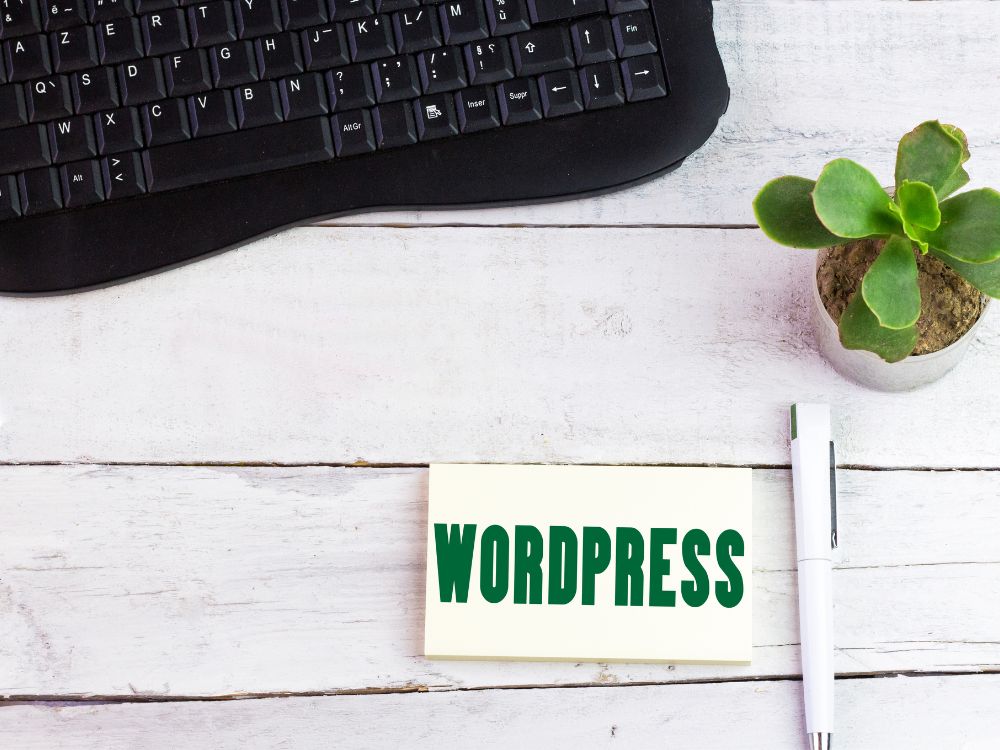 Teclado, planta e caderno com a palavra WordPress, simbolizando busca pelos melhores plugins para WordPress.