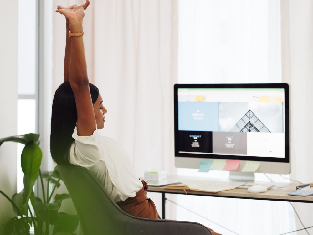 Mulher relaxando em frente ao computador com site aberto na tela, expressando facilidade na gestão de conteúdo porque WordPress é CMS intuitivo.