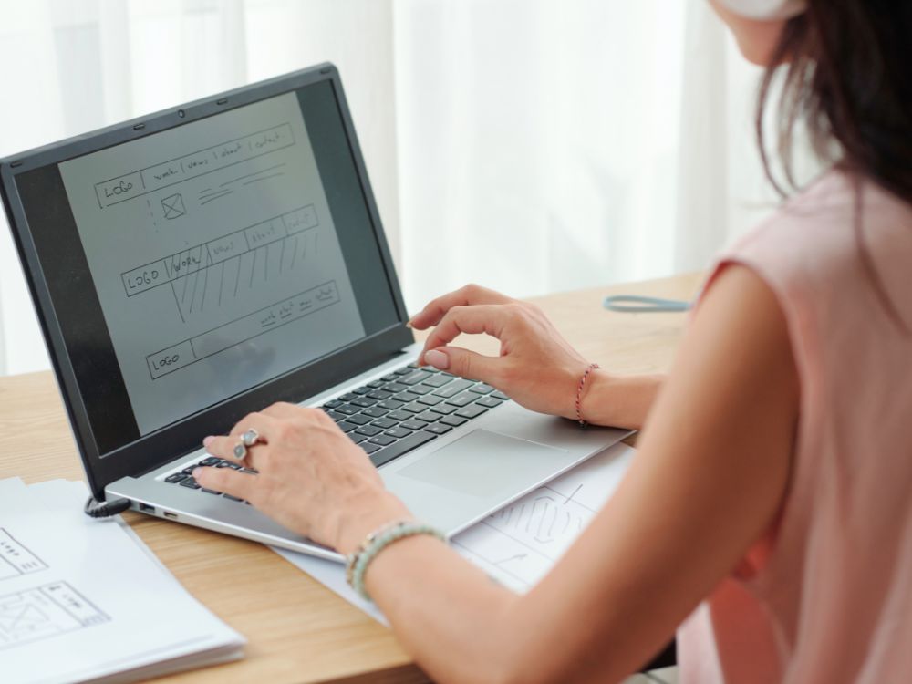 Profissional desenhando layout no notebook, etapa que mostra Quanto tempo leva para criar um site do planejamento ao desenvolvimento