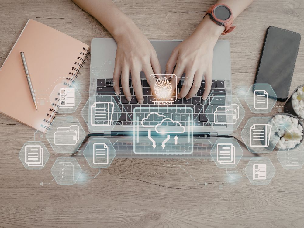 Pessoa trabalhando em notebook com recursos de armazenamento em nuvem e gestão de documentos, representando ações de posicionamento digital e transformação digital.